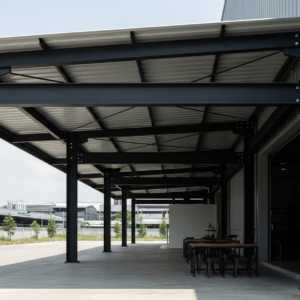 Apa keunggulan profil WF dibanding hollow biasa untuk kanopi industrial? -> Profil WF (Wide Flange) memiliki bentuk penampang huruf H yang memberikan momen inersia jauh lebih tinggi dibanding hollow persegi. Artinya: lebih kaku, lebih kuat menahan beban lentur, dan mampu menjangkau span lebar tanpa tiang tengah. Untuk kanopi industrial yang mengutamakan kekuatan ekspos dan efisiensi ruang, WF adalah pilihan struktural yang superior. Apakah finishing raw steel ini tidak cepat berkarat di cuaca Medan? -> Raw steel finishing kami dilapisi clear coat marine-grade yang khusus diformulasikan untuk iklim tropis. Lapisan ini melindungi dari korosi sambil membiarkan karakter alami besi tetap terlihat. Untuk area dengan kelembapan ekstrem atau dekat pantai, kami rekomendasikan tambahan coating zinc-rich primer sebelum clear coat untuk proteksi ekstra. Berapa panjang span maksimal yang bisa dicapai dengan kanopi WF ini? -> Dengan profil WF 150x75mm, span aman hingga 6 meter. Untuk WF 200x100mm, bisa mencapai 8-10 meter dengan kalkulasi engineering yang tepat. Tim kami akan hitung dan rekomendasikan profil optimal berdasarkan kebutuhan span, beban atap, dan kondisi lokasi Anda. Bisakah kanopi ini diintegrasikan dengan sistem drainase atau lighting? -> Sangat bisa. Profil WF memiliki flange lebar yang memudahkan integrasi: (1) saluran talang dapat dipasang di sisi dalam flange tanpa mengganggu estetika, (2) conduit listrik untuk lighting dapat di-clamp ke web profil dengan bracket custom. Tim kami akan diskusikan detail integrasi saat tahap desain.